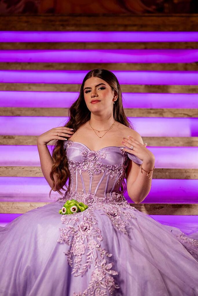 Debutante em vestido lilás sentada nos degraus da escadaria iluminada