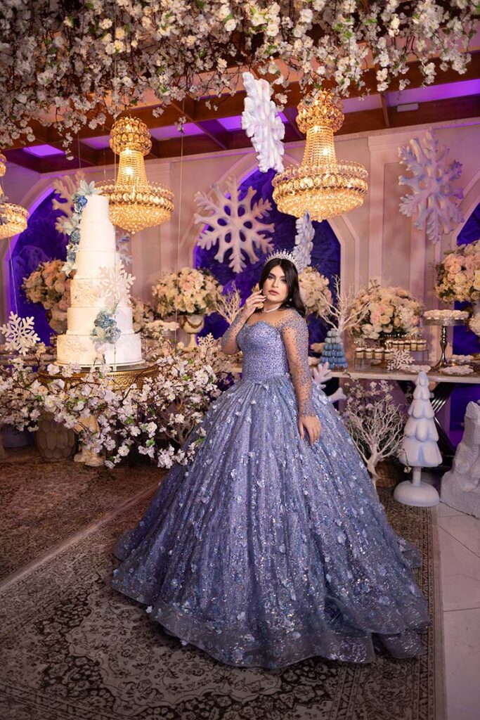 Debutante em vestido azul ao lado da mesa do bolo do inverno encantado