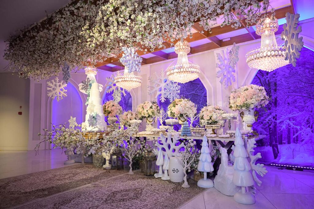 Salão do inverno encantado com flores suspensas, lustres e mesa do bolo