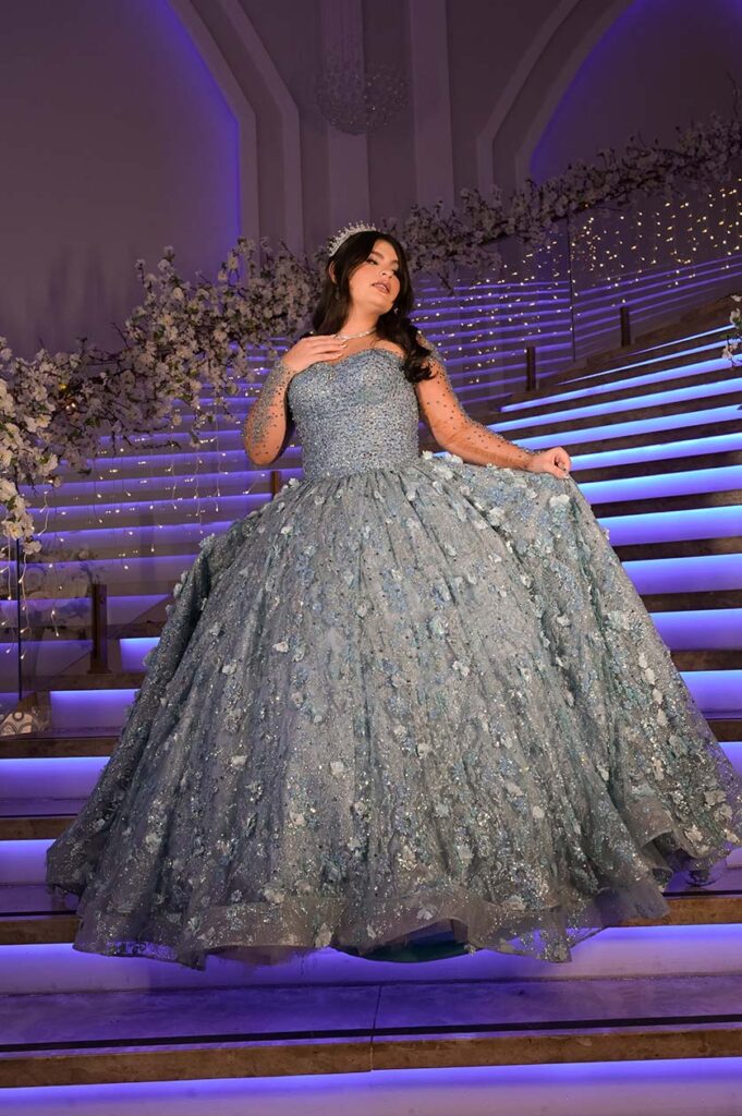 Debutante em vestido azul desce a escadaria iluminada