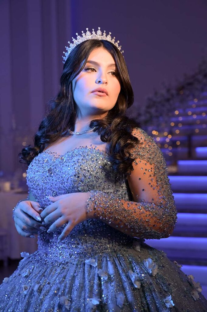 Debutante em vestido azul diante da escadaria iluminada