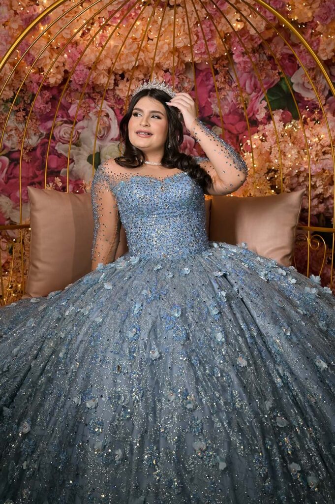 Debutante sentada em poltrona diante do arco de flores em tons quentes