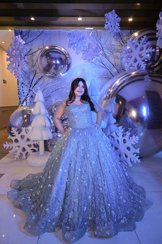 Debutante em vestido azul entre flocos de neve e esferas espelhadas