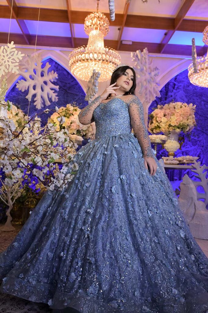 Debutante em vestido azul diante da decoração com flocos de neve