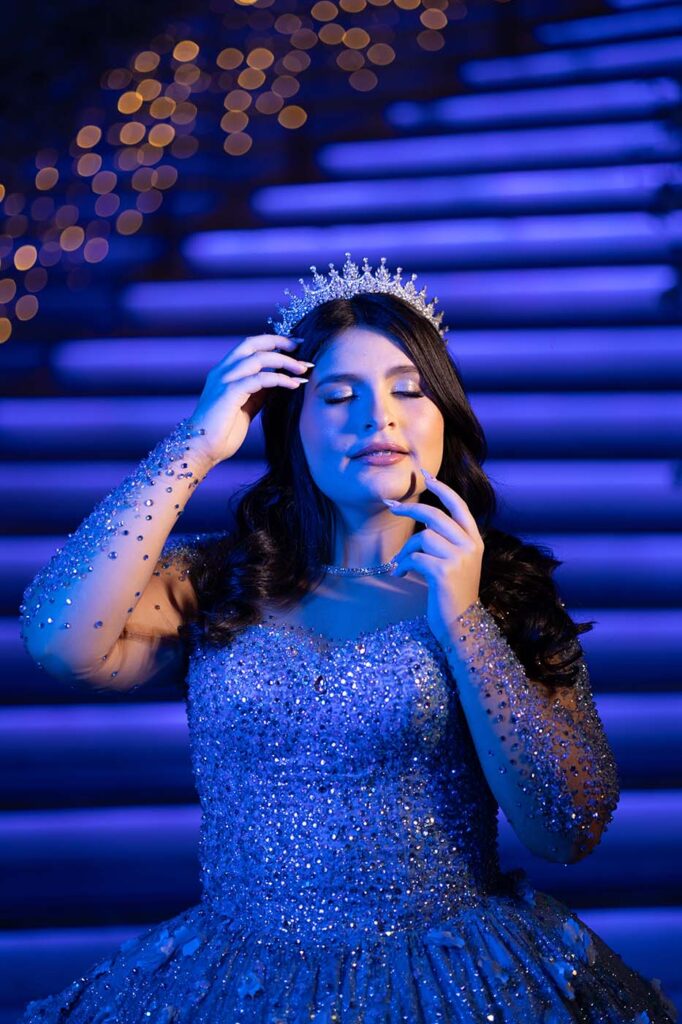 Debutante em vestido azul diante da escadaria iluminada em azul