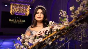 Debutante apoiada no corrimão da escadaria decorada com flores