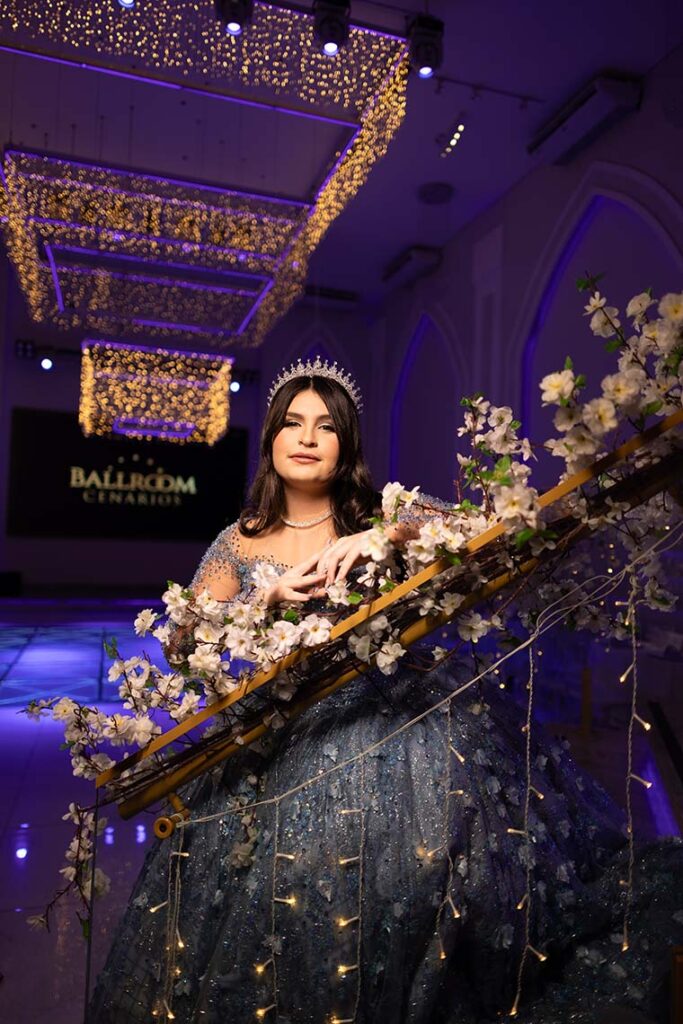Debutante apoiada no corrimão da escadaria decorada com flores
