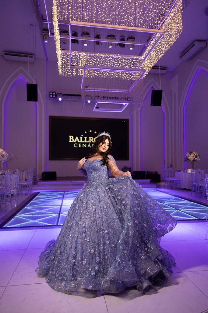 Debutante em vestido azul na pista iluminada do salão