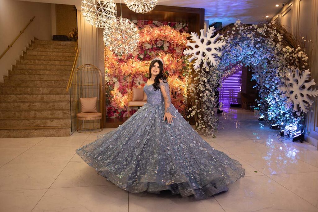 Debutante em vestido azul entre flocos de neve gigantes e flores