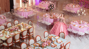 Debutante em vestido rosa no salão montado com mesas decoradas