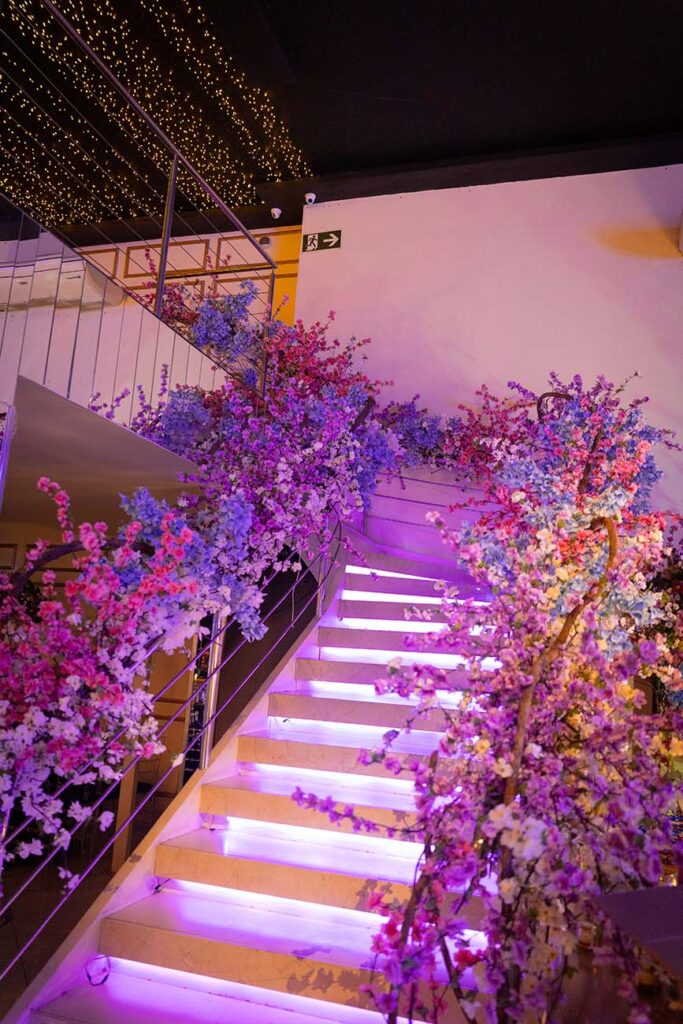 Escadaria iluminada decorada com flores em tons de rosa e lilás