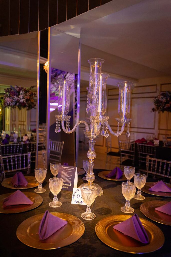 Mesa dos convidados com candelabros de cristal e guardanapos roxos