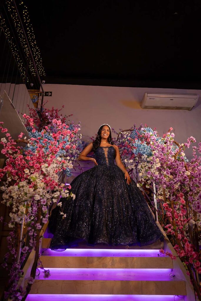 Debutante em vestido roxo no alto da escadaria iluminada