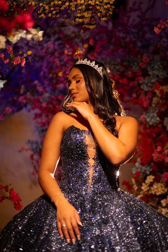 Retrato da debutante com coroa e vestido roxo bordado entre flores