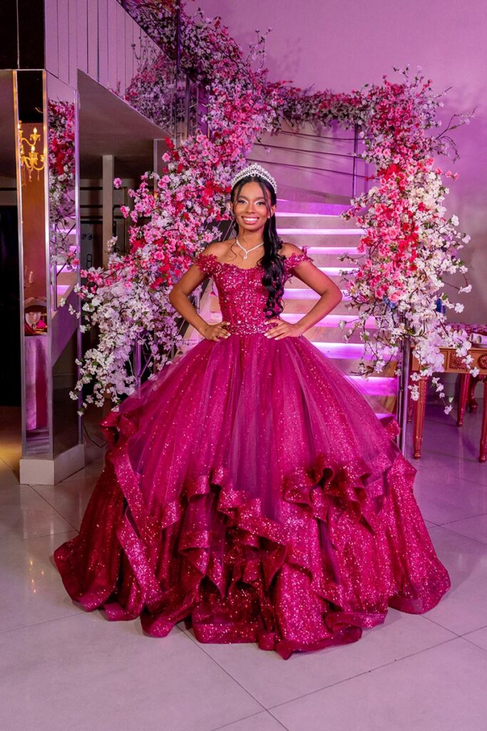 Debutante em vestido pink diante da parede de flores