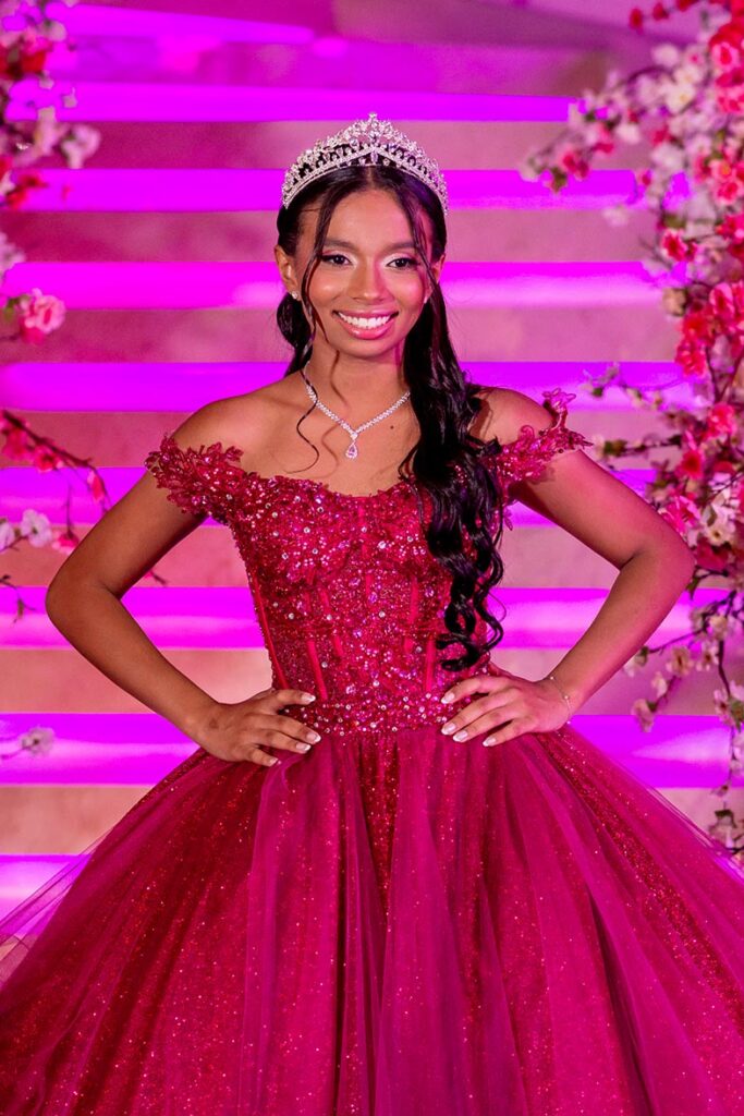 Debutante em vestido pink de baile ao pé da escadaria iluminada