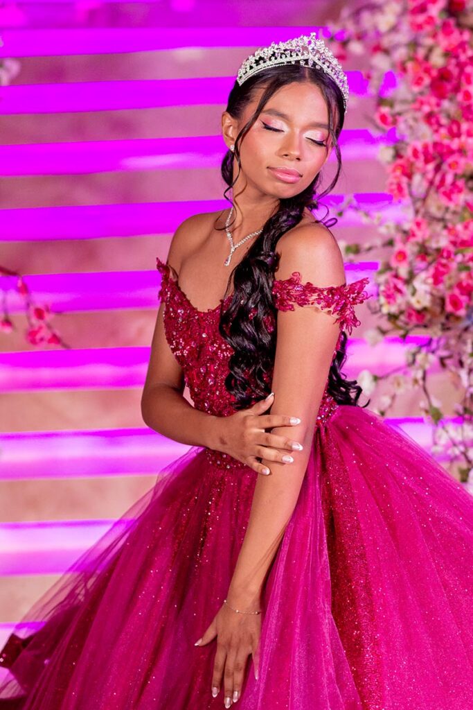 Debutante em vestido pink diante da escadaria iluminada em rosa