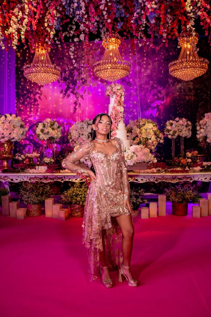 Debutante no segundo look dourado ao lado da mesa do bolo