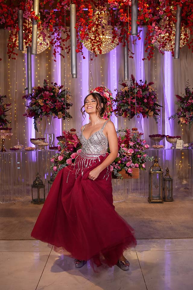 Debutante roda o vestido vinho diante da decoração em vermelho