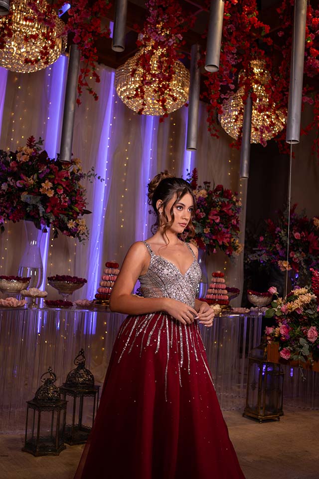 Debutante em vestido vinho apoiada na mesa do bolo