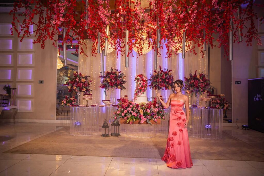 Debutante em vestido vinho no salão decorado com flores vermelhas