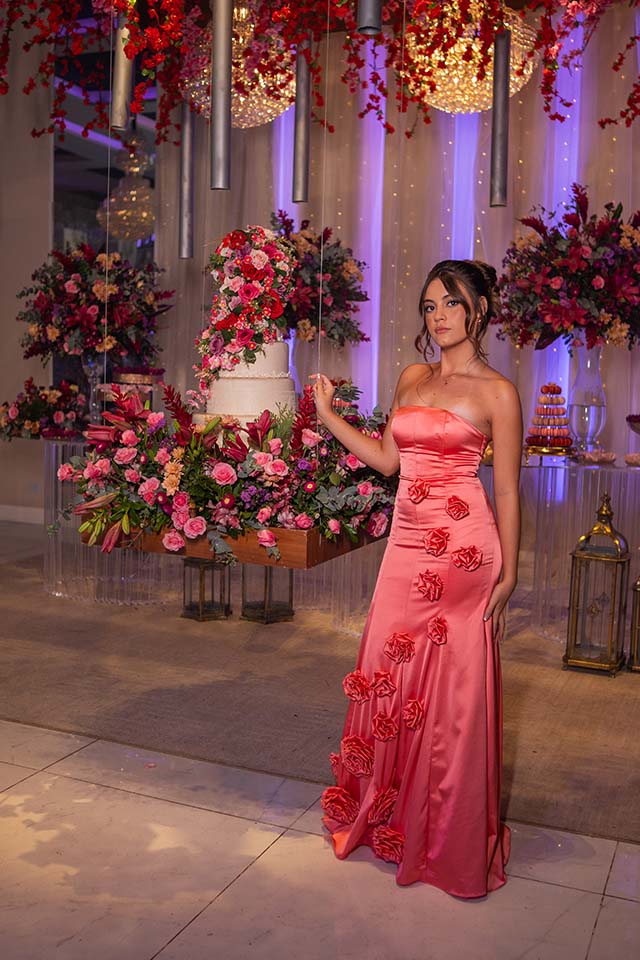 Debutante no segundo look coral diante da decoração em vermelho