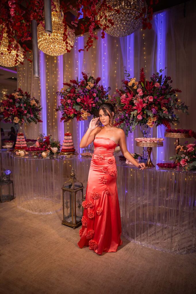 Debutante no segundo look coral diante da mesa do bolo