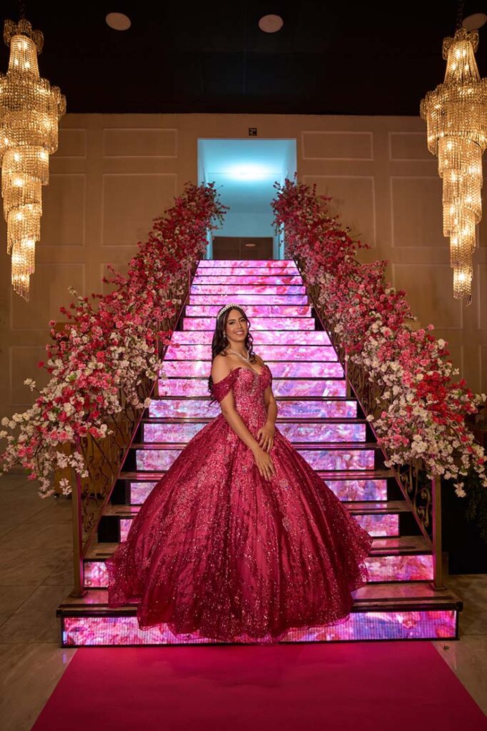Debutante em vestido pink ao pé da escadaria de LED