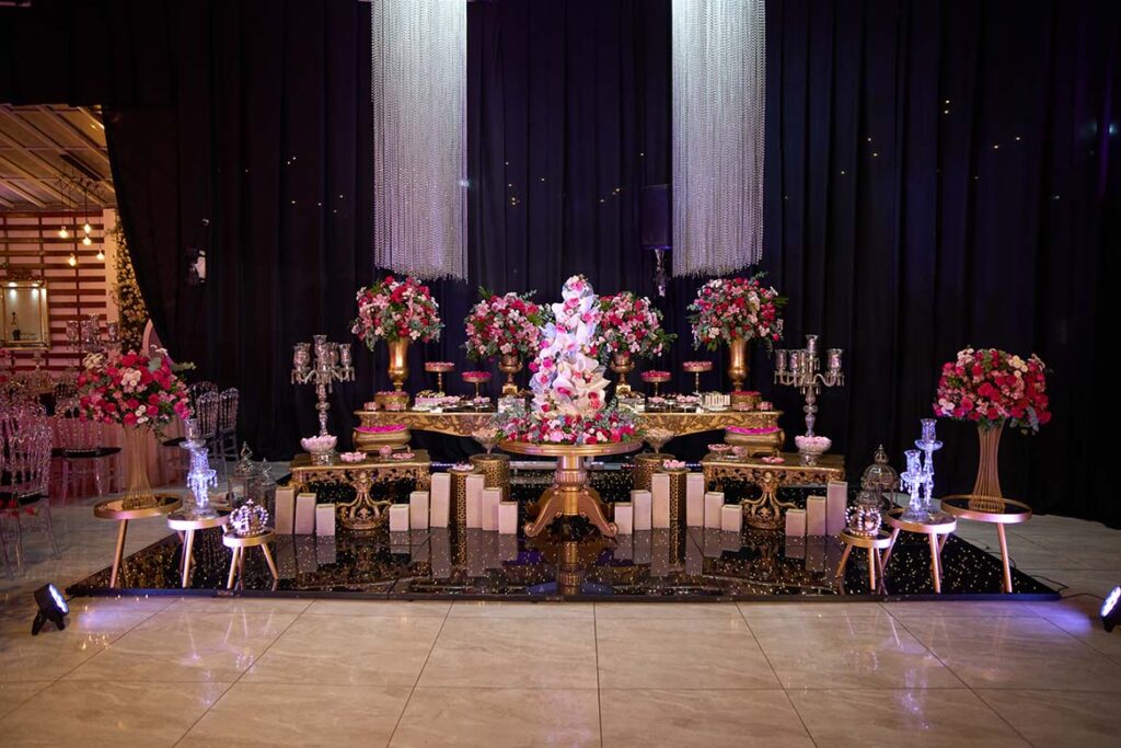 Mesa do bolo com candelabros e arranjos de flores