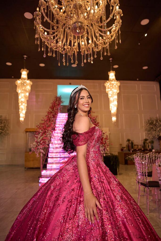 Debutante em vestido pink diante da escadaria iluminada