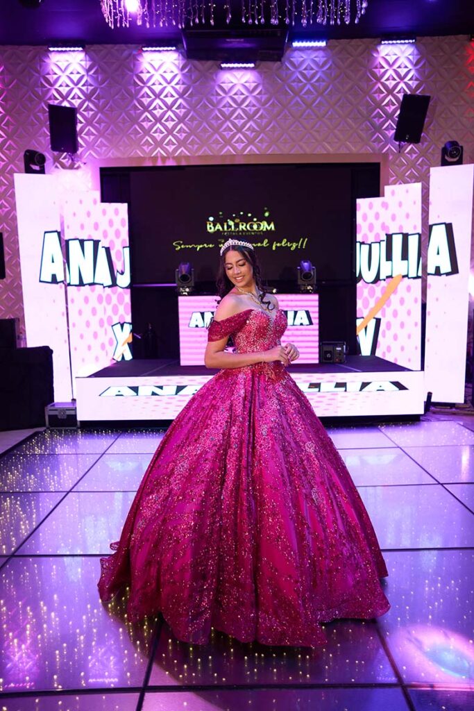Debutante em vestido pink diante do painel de LED com seu nome