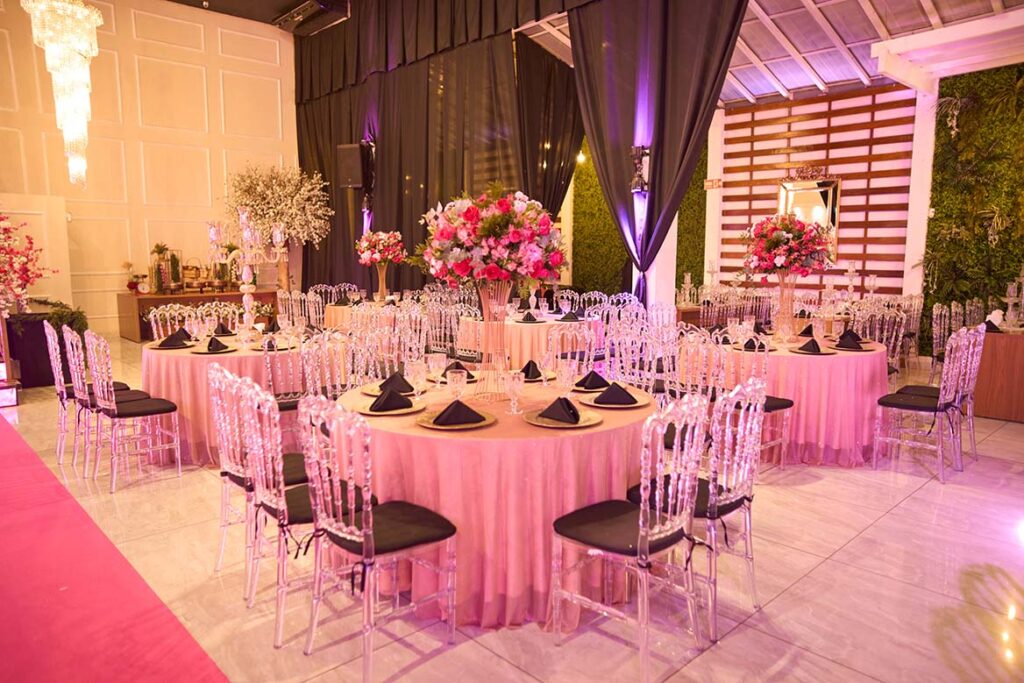 Mesas dos convidados com toalhas rosa e arranjos florais