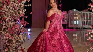 Debutante em vestido pink sob o arco de flores da entrada
