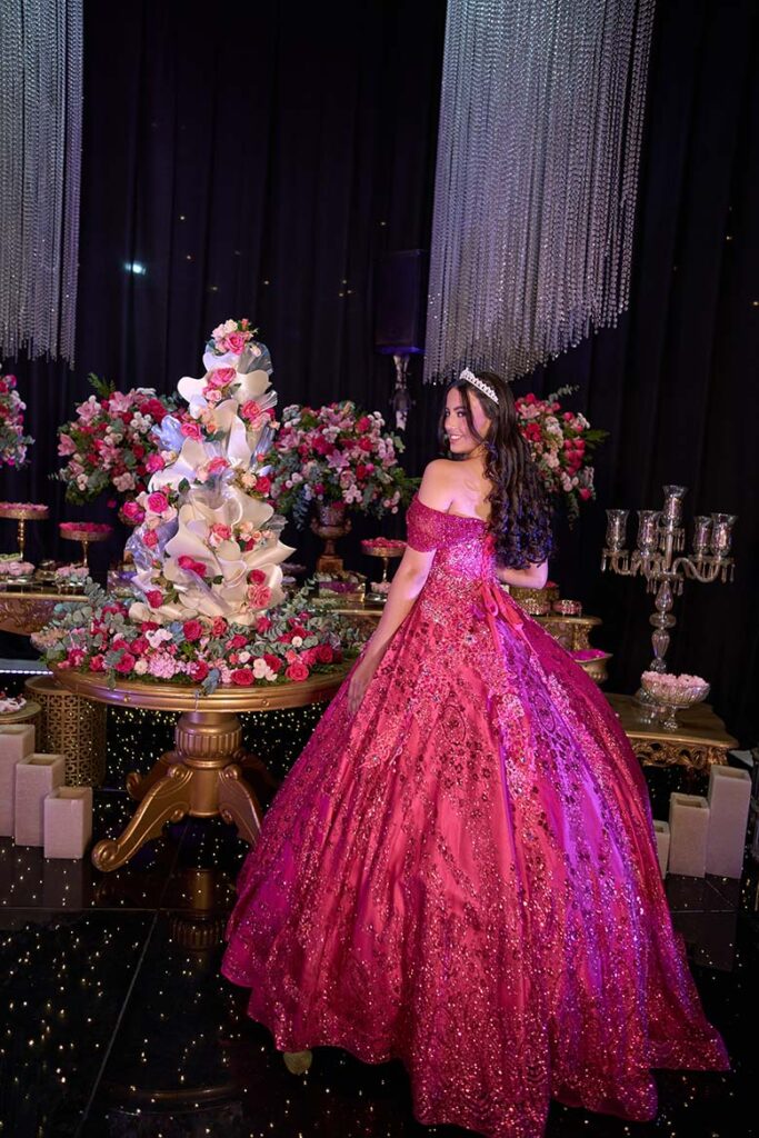 Debutante em vestido pink ao lado da mesa do bolo