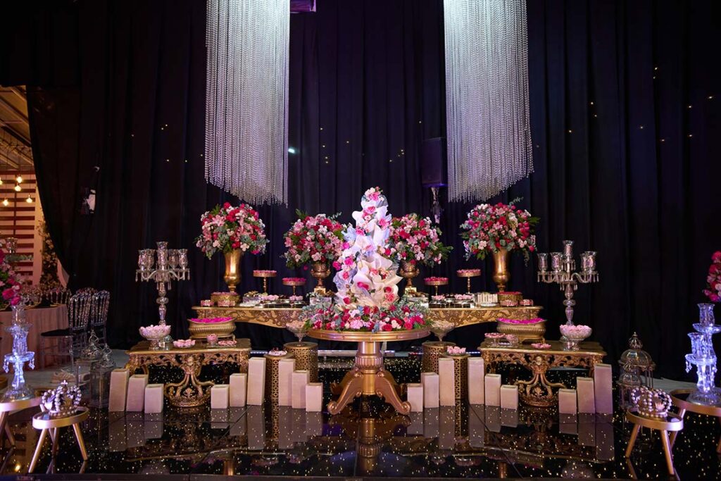 Mesa do bolo iluminada com flores em tons de rosa e branco