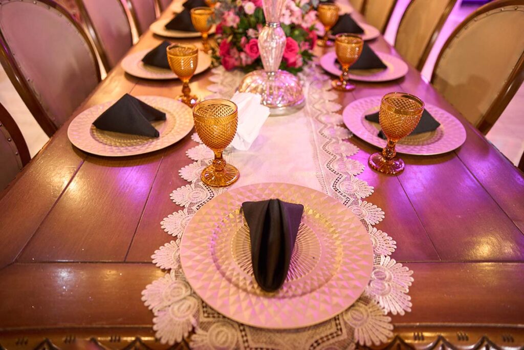 Detalhe da mesa posta com sousplat rosa e taça dourada