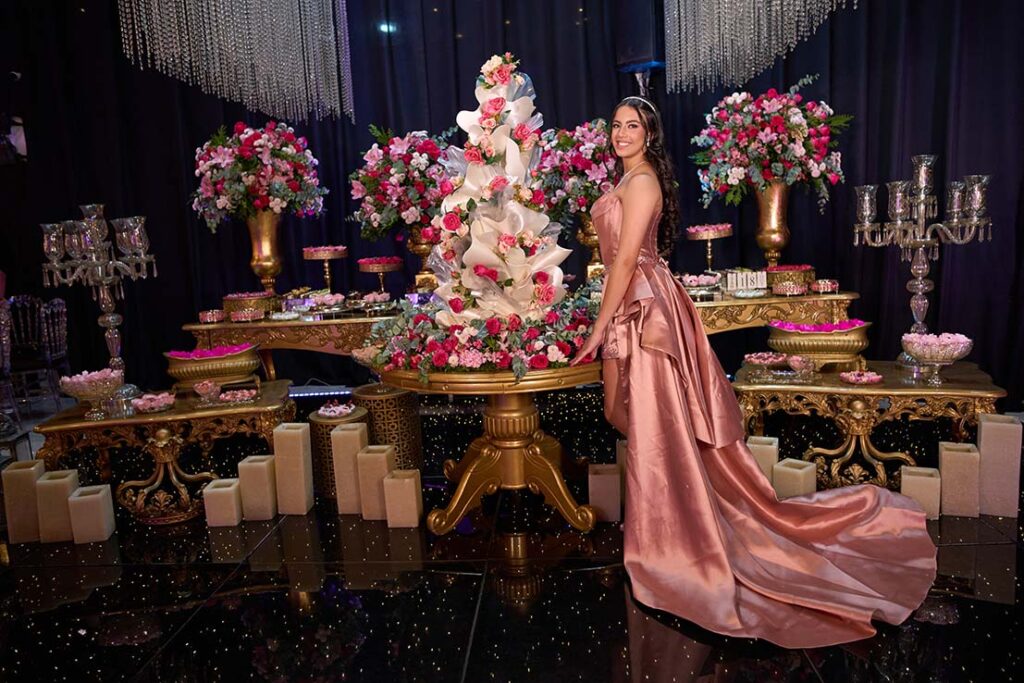 Debutante no segundo look diante da mesa do bolo com a cauda estendida