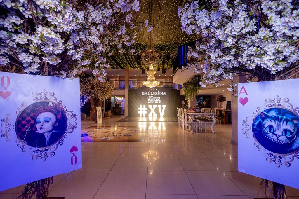 Entrada decorada com cartas de baralho gigantes e árvores floridas