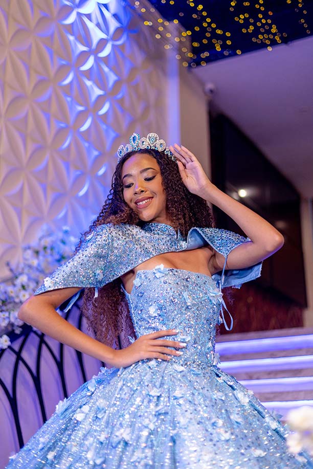 Debutante em vestido azul com capa diante da escadaria