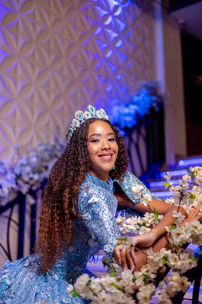 Debutante sentada entre arranjos de flores e vegetação suspensa
