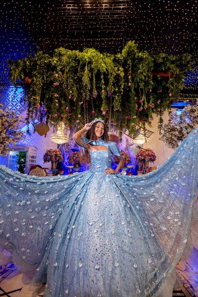 Debutante em vestido azul sob a vegetação suspensa do cenário