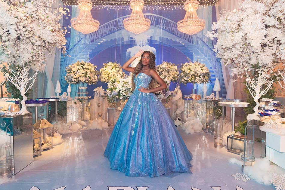 Debutante em vestido azul diante do cenário com flores e árvores brancas
