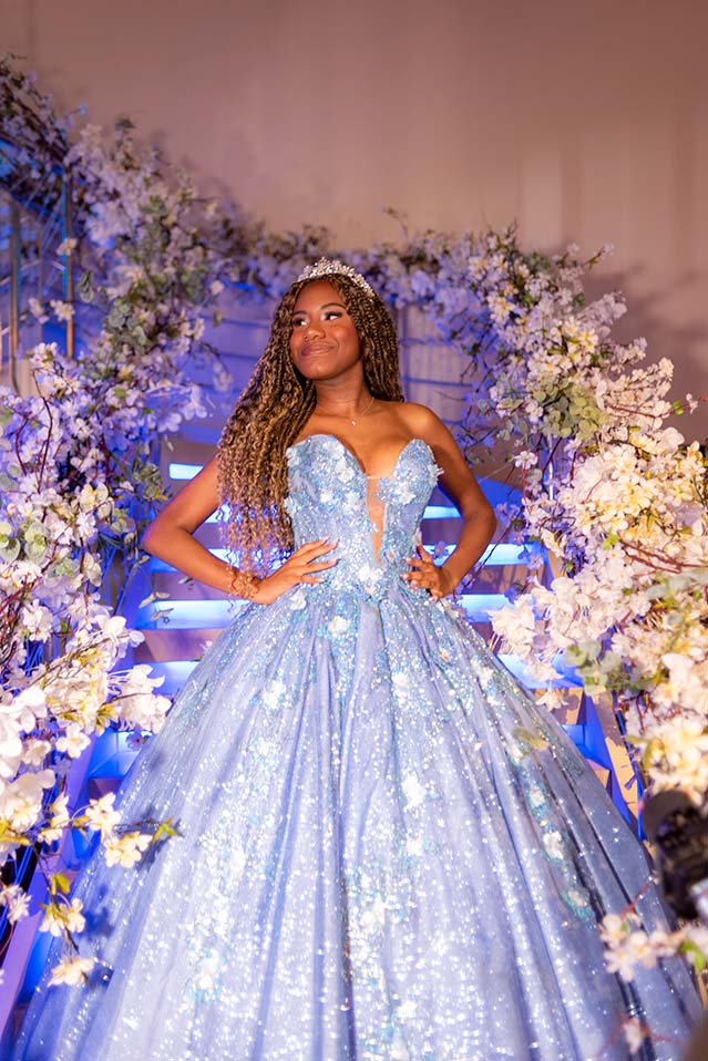 Debutante em vestido azul emoldurada por flores brancas