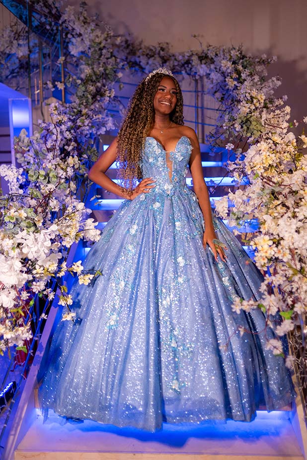 Debutante em vestido azul entre os arranjos florais do cenário