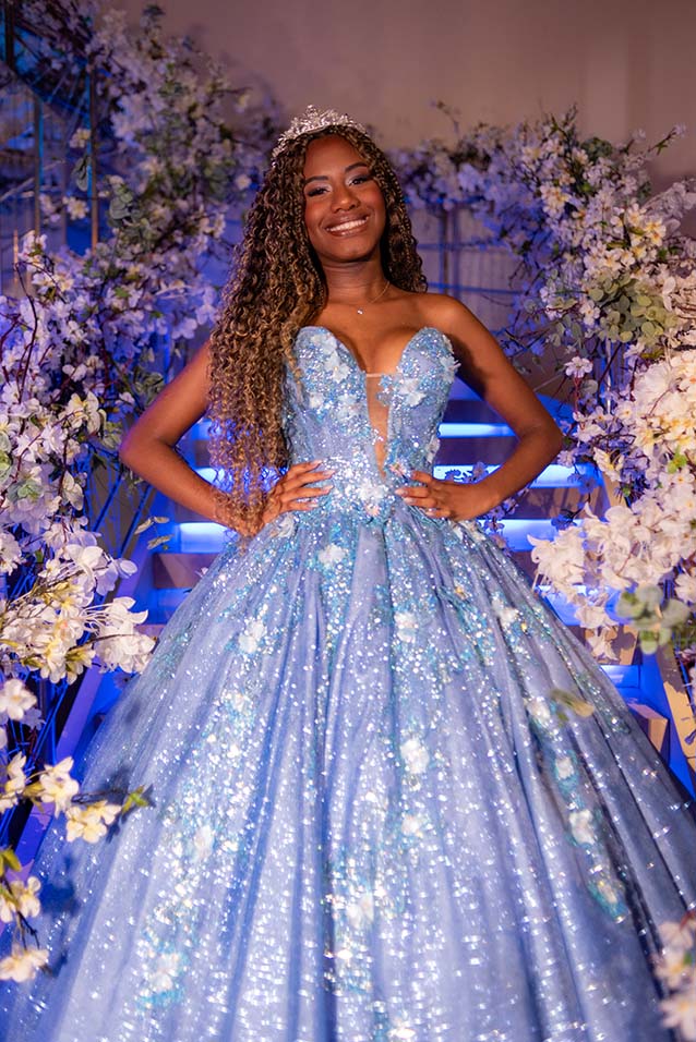 Debutante em vestido azul entre arranjos de flores brancas