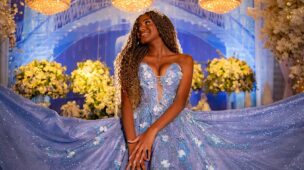 Debutante sentada com o vestido azul espalhado diante das flores
