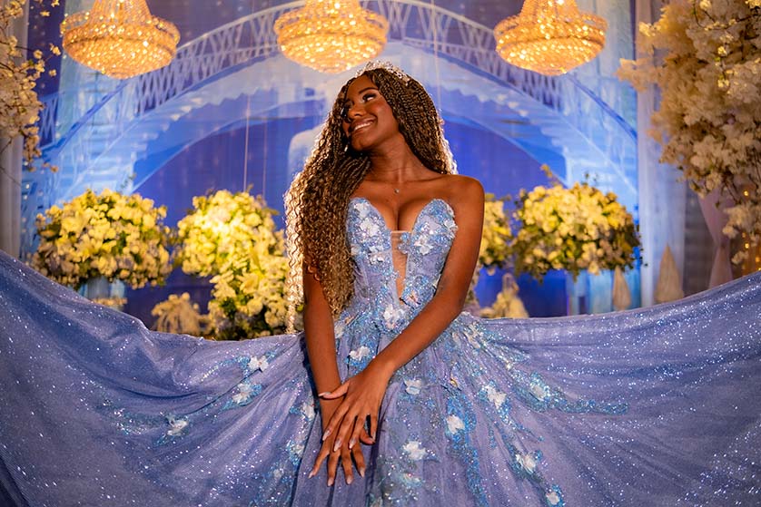 Debutante sentada com o vestido azul espalhado diante das flores
