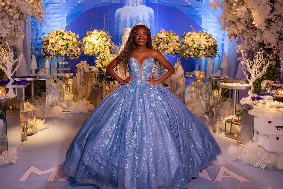 Debutante em vestido azul entre os arranjos de flores do cenário
