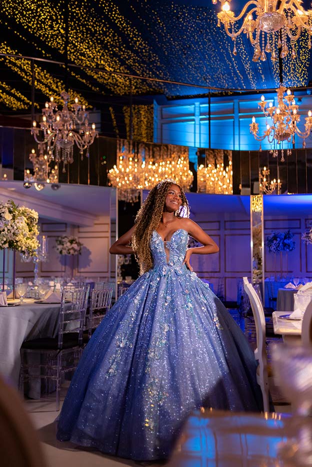 Debutante em vestido azul sob os lustres de cristal do salão