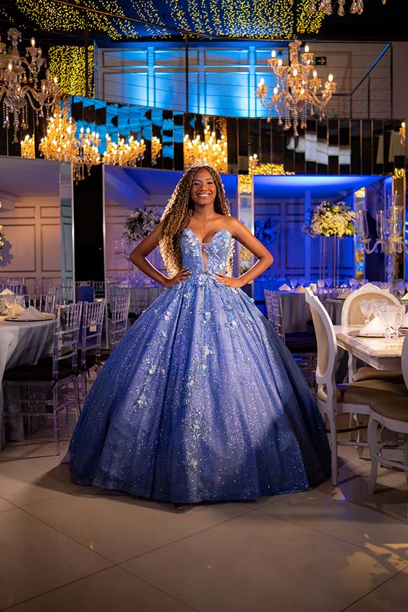 Debutante em vestido azul entre as mesas dos convidados